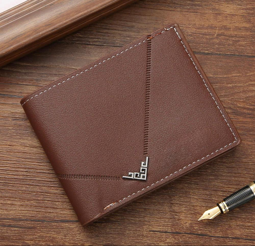 Brown leather wallet on a wooden surface with a pen next to it